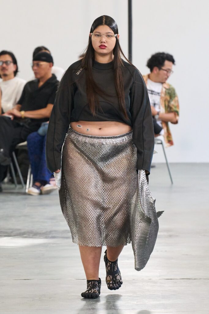 A fitted black crop top paired with an asymmetric layered silver mesh skirt.
