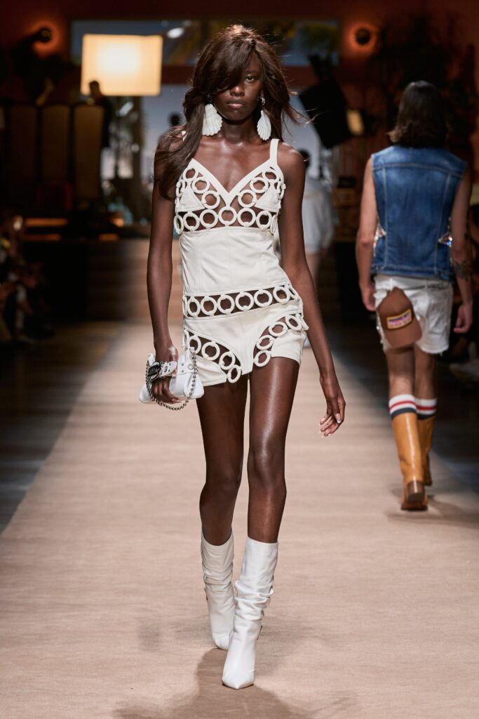 A fitted white sleeveless dress with a V-neckline and tiered design details.