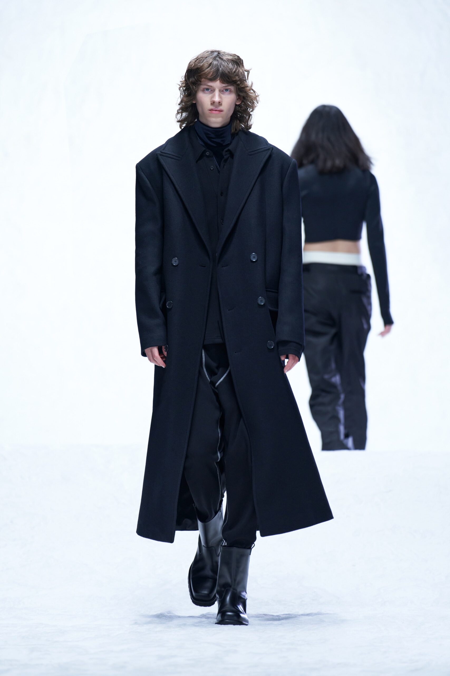 A relaxed black wool coat with long sleeves and a collared design, paired with matching pants.