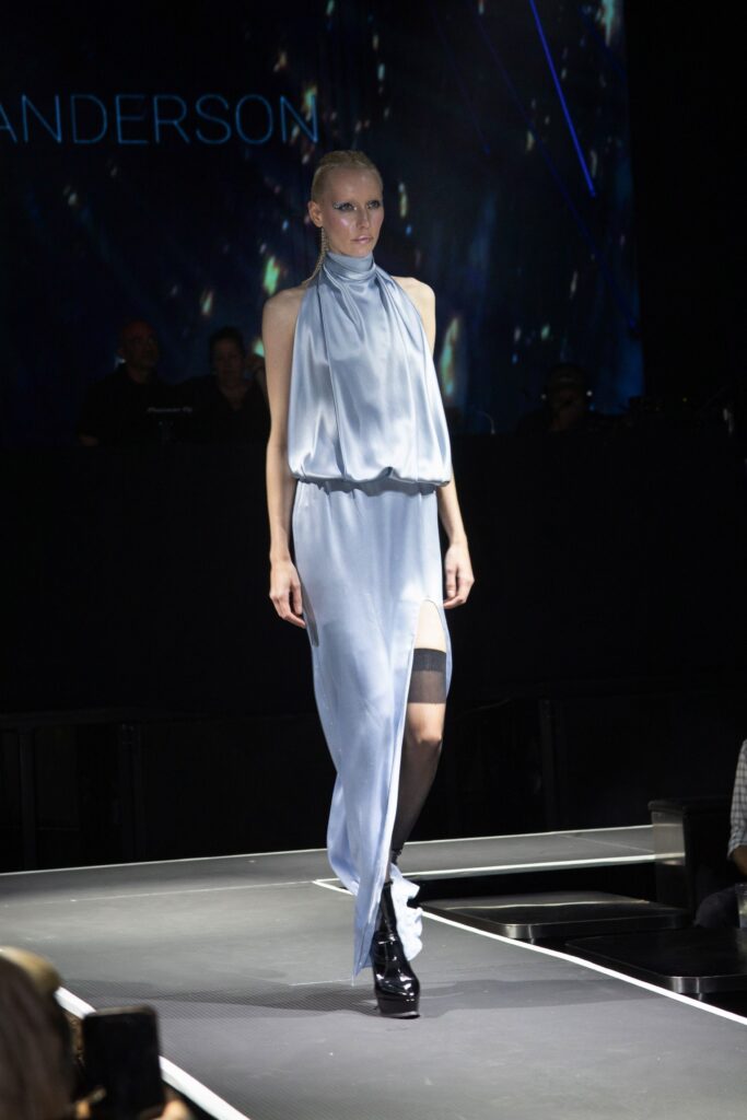 A relaxed blue silk sleeveless dress with a high neckline and asymmetric slit detail.