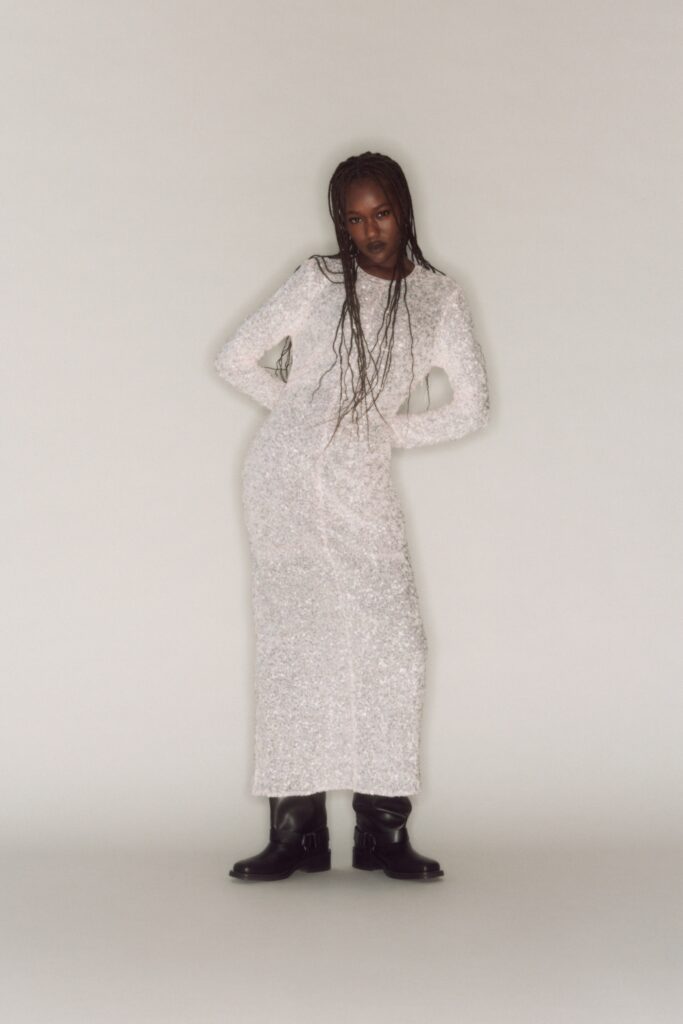 A fitted white sheer dress with long sleeves and a high neckline.
