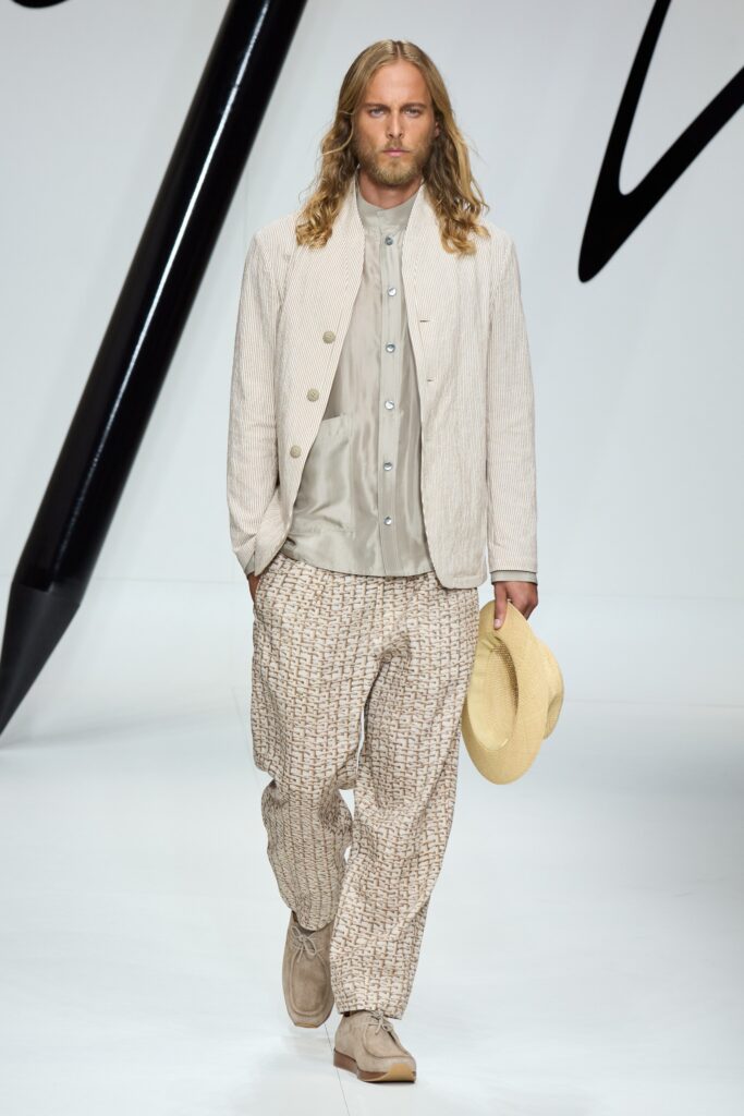 A relaxed beige cotton jacket with long sleeves and collared design, paired with printed pants.