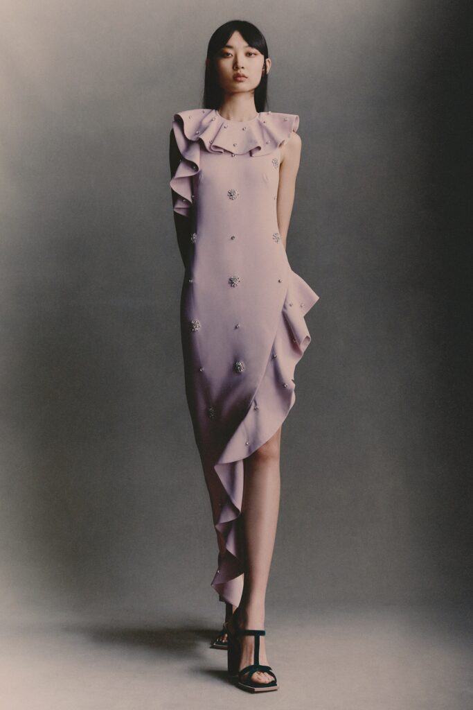 A fitted purple silk dress with a high neckline and ruffled asymmetric design.