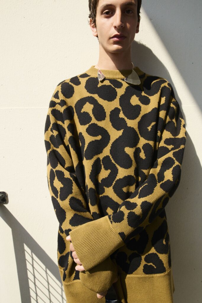 An oversized brown sweater featuring a bold black leopard print design and long sleeves.