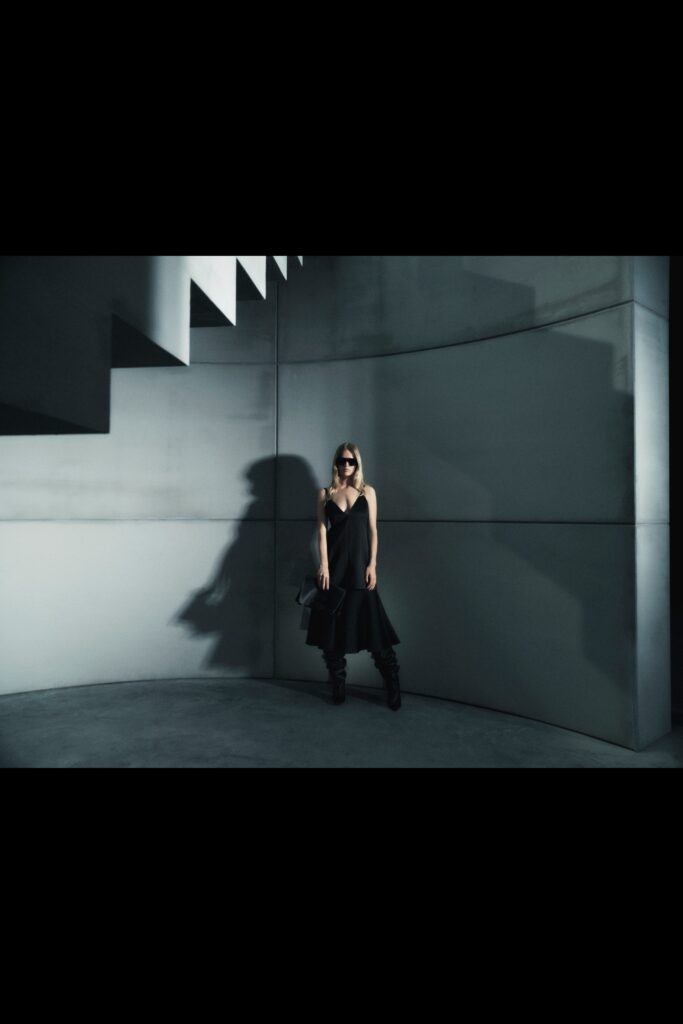 A fitted black silk sleeveless dress with a V-neckline and asymmetric design.