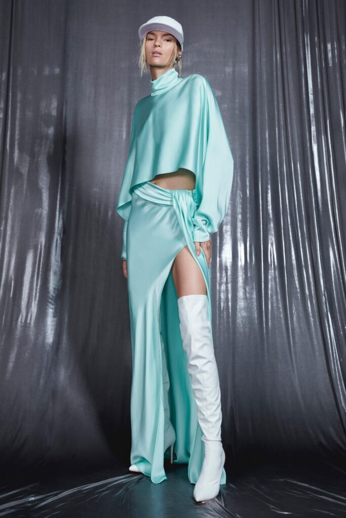 A fitted aqua silk dress with long sleeves, high neckline, and an asymmetric slit detail.