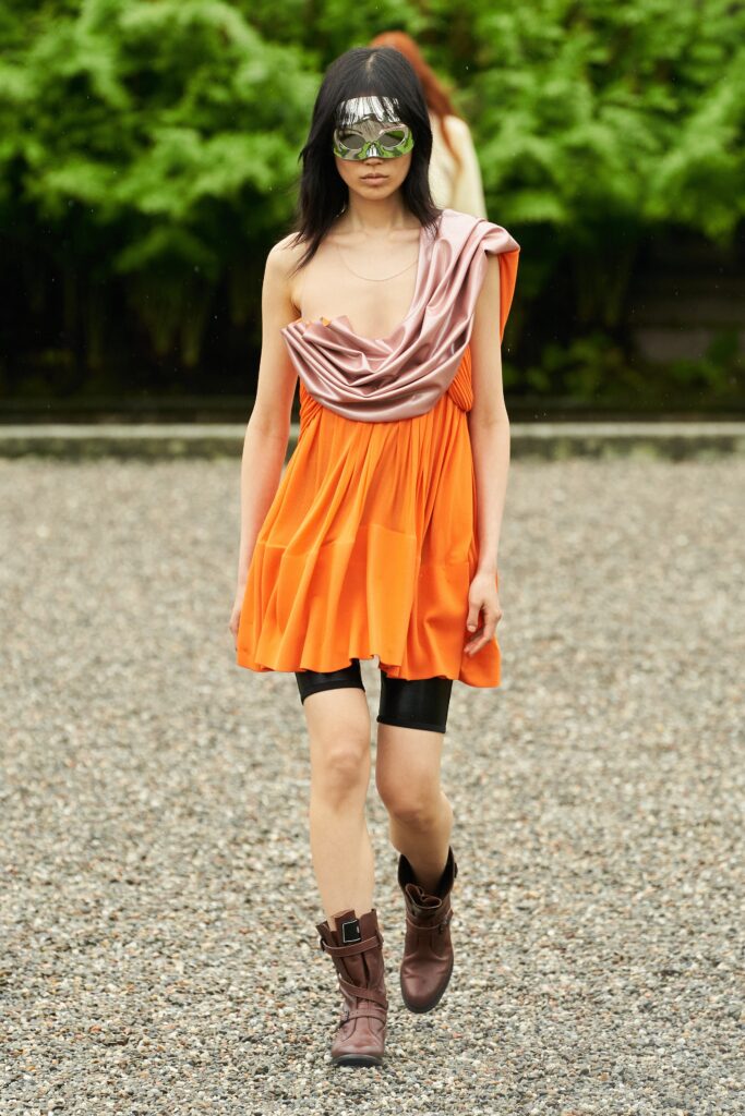 A fitted orange silk dress with a sleeveless design and pleated details.