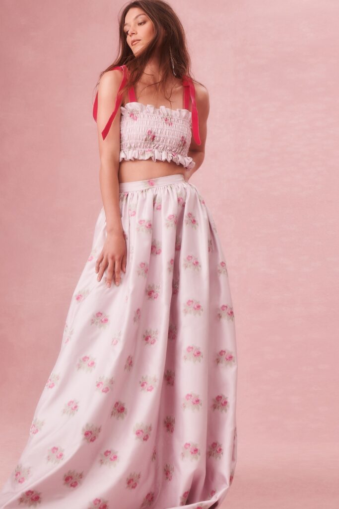 A fitted pink floral crop-top paired with a tiered maxi-dress, featuring a sleeveless design.