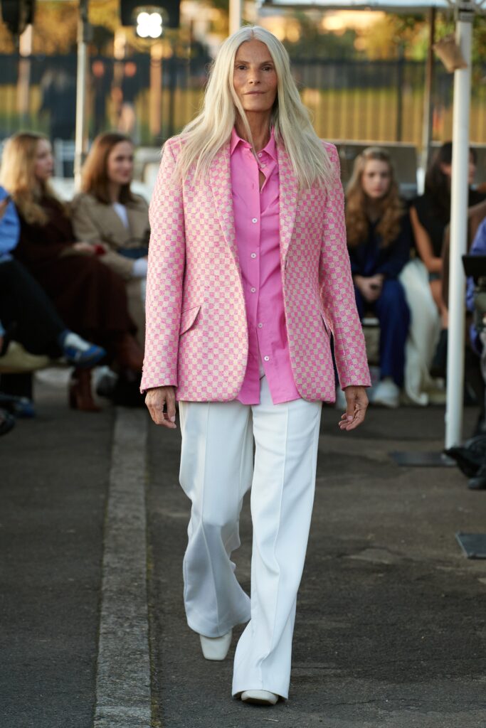 A fitted pink checked blazer paired with white pants, featuring a collared neckline and long sleeves.