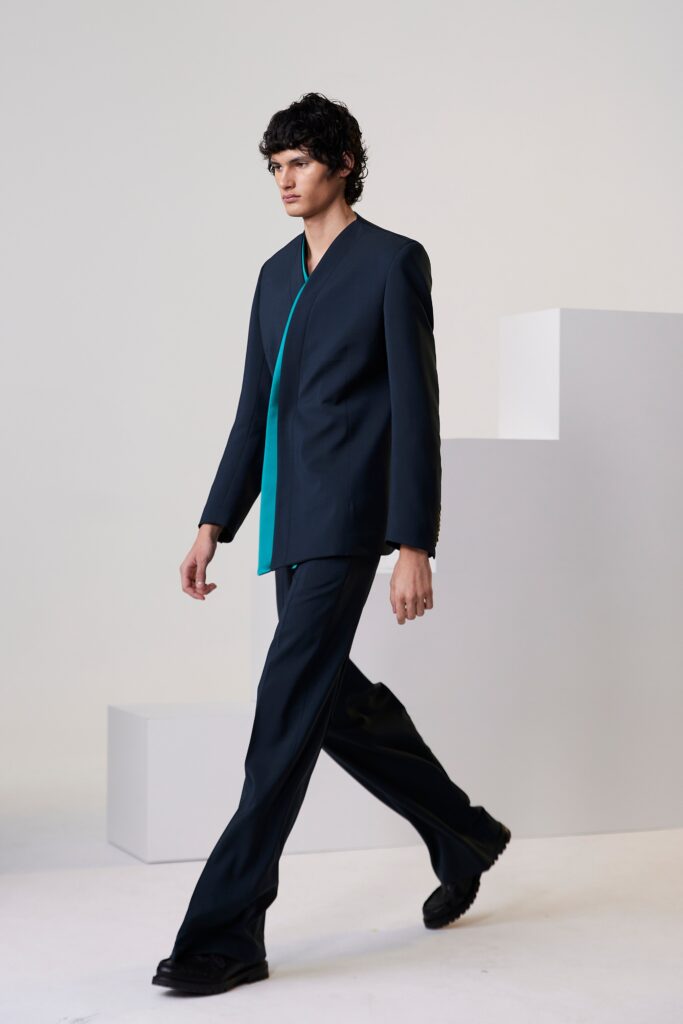 A tailored navy suit with a teal accent and asymmetric design details.
