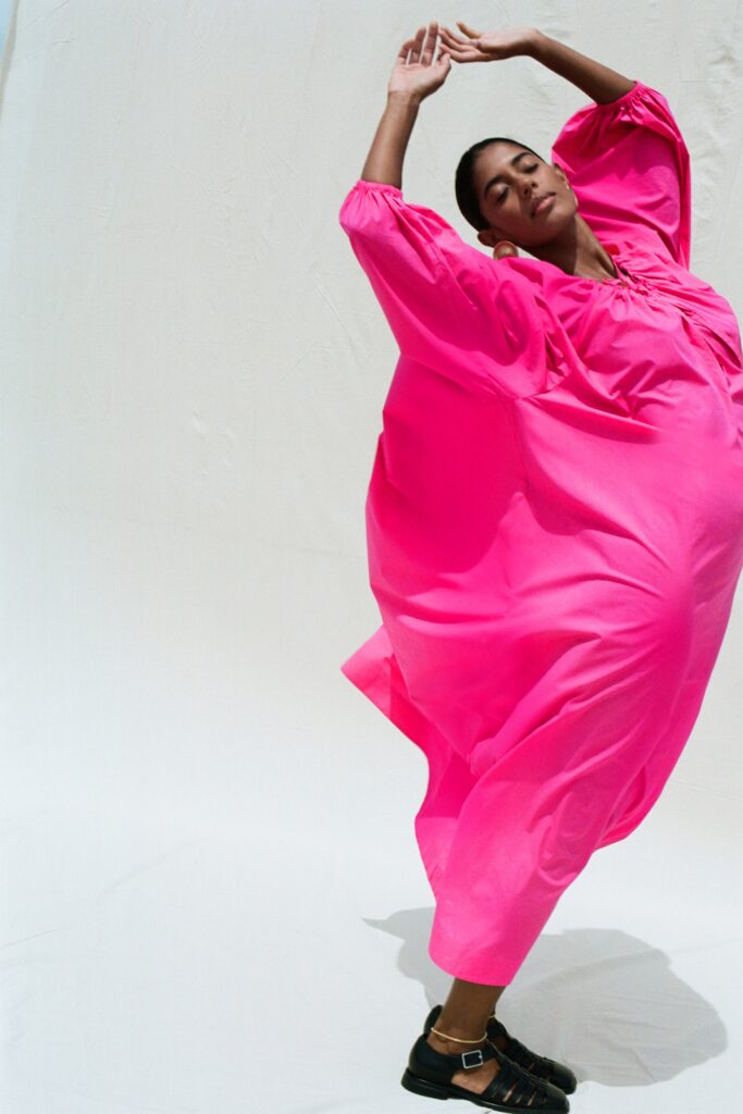 An oversized pink cotton dress with long sleeves and a tiered design.