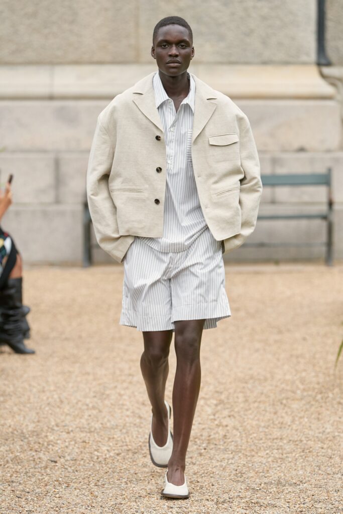 A relaxed beige cotton jacket paired with striped shorts for a casual look.