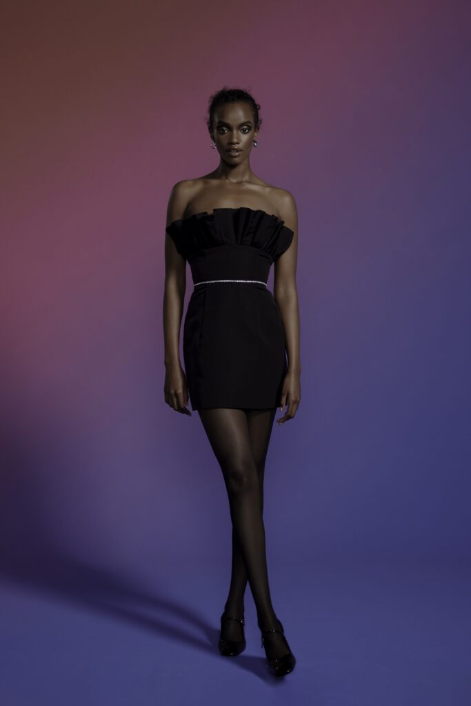 A fitted black silk dress with a strapless design and pleated details.