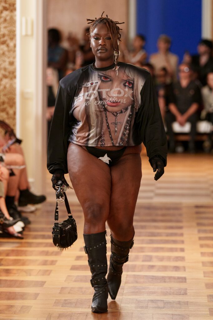 An oversized black sleeveless top paired with high-waisted black shorts for a bold look.