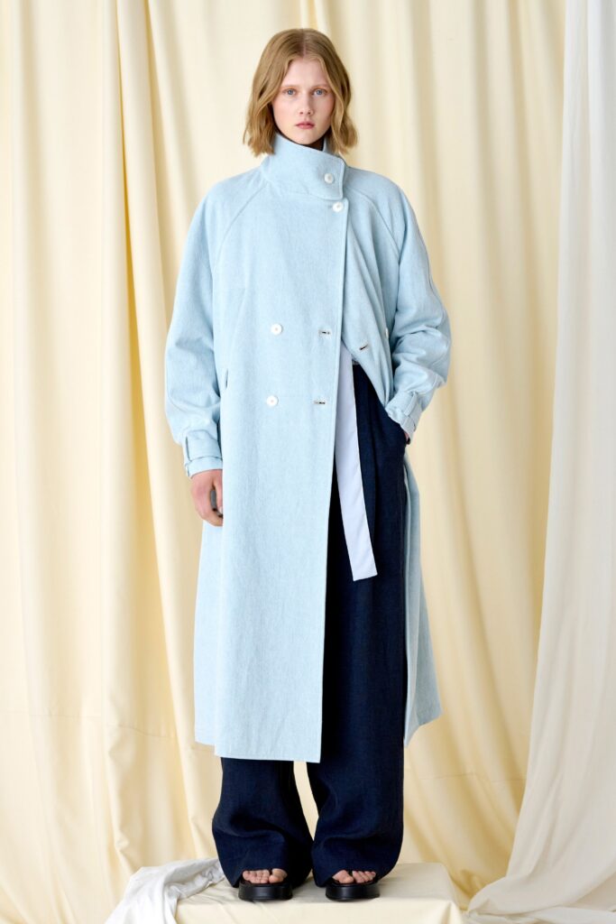A relaxed blue denim coat with long sleeves, paired with wide-leg black pants.
