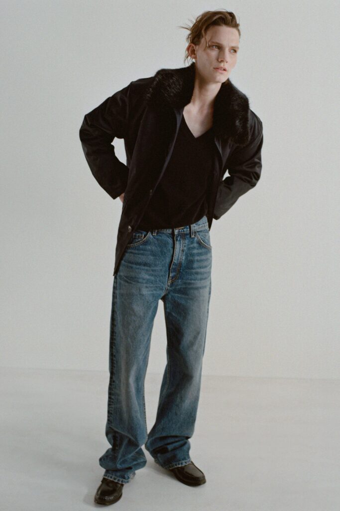 A relaxed black leather jacket paired with relaxed blue denim jeans and a V-neck top.
