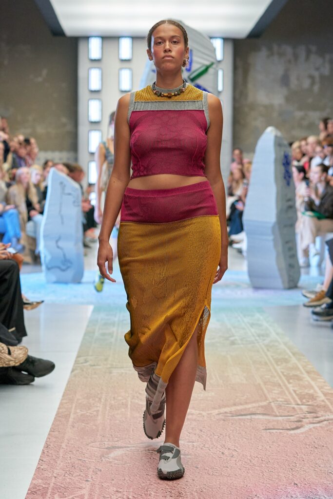 A fitted sleeveless dress in red and yellow with an asymmetric and tiered design.