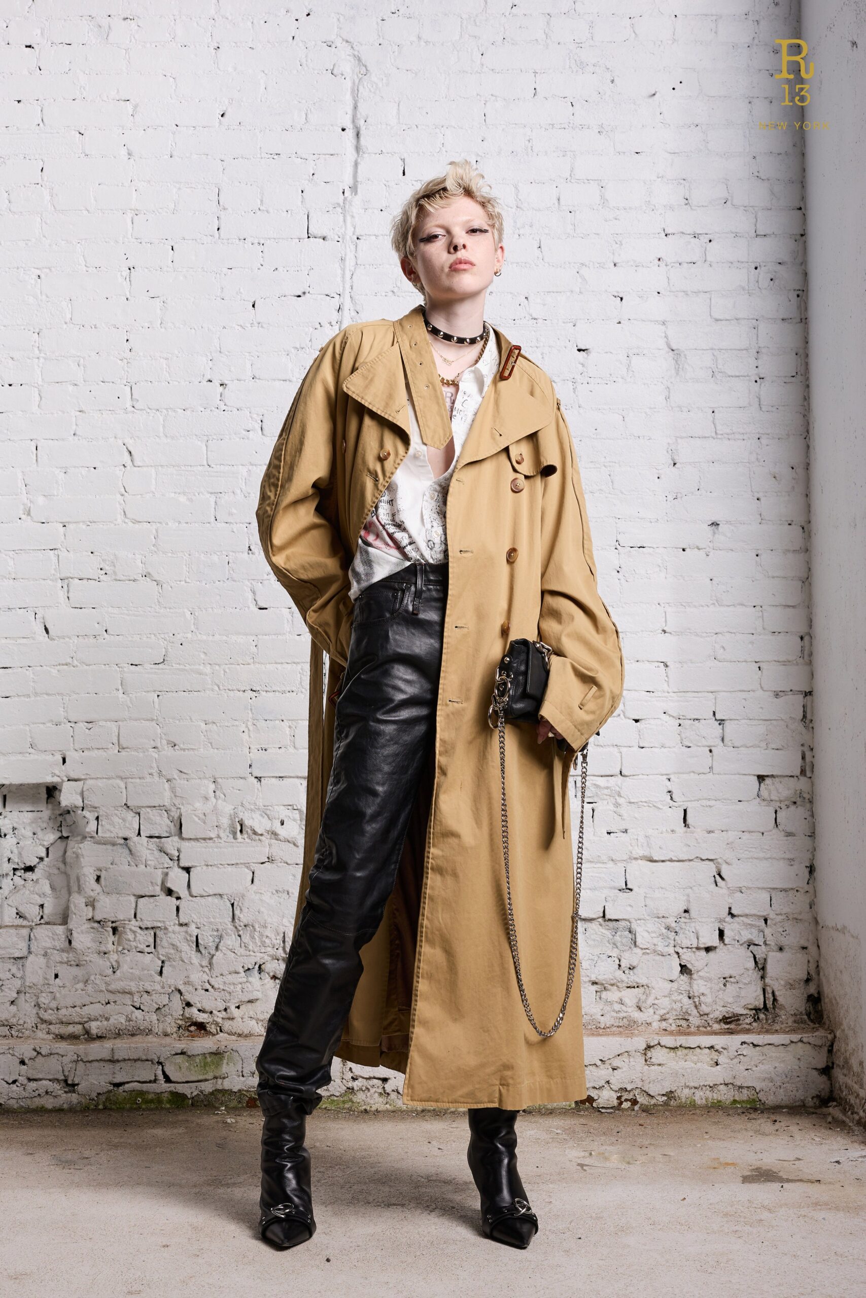 A fitted beige coat with a collared design paired with straight-leg black leather pants.
