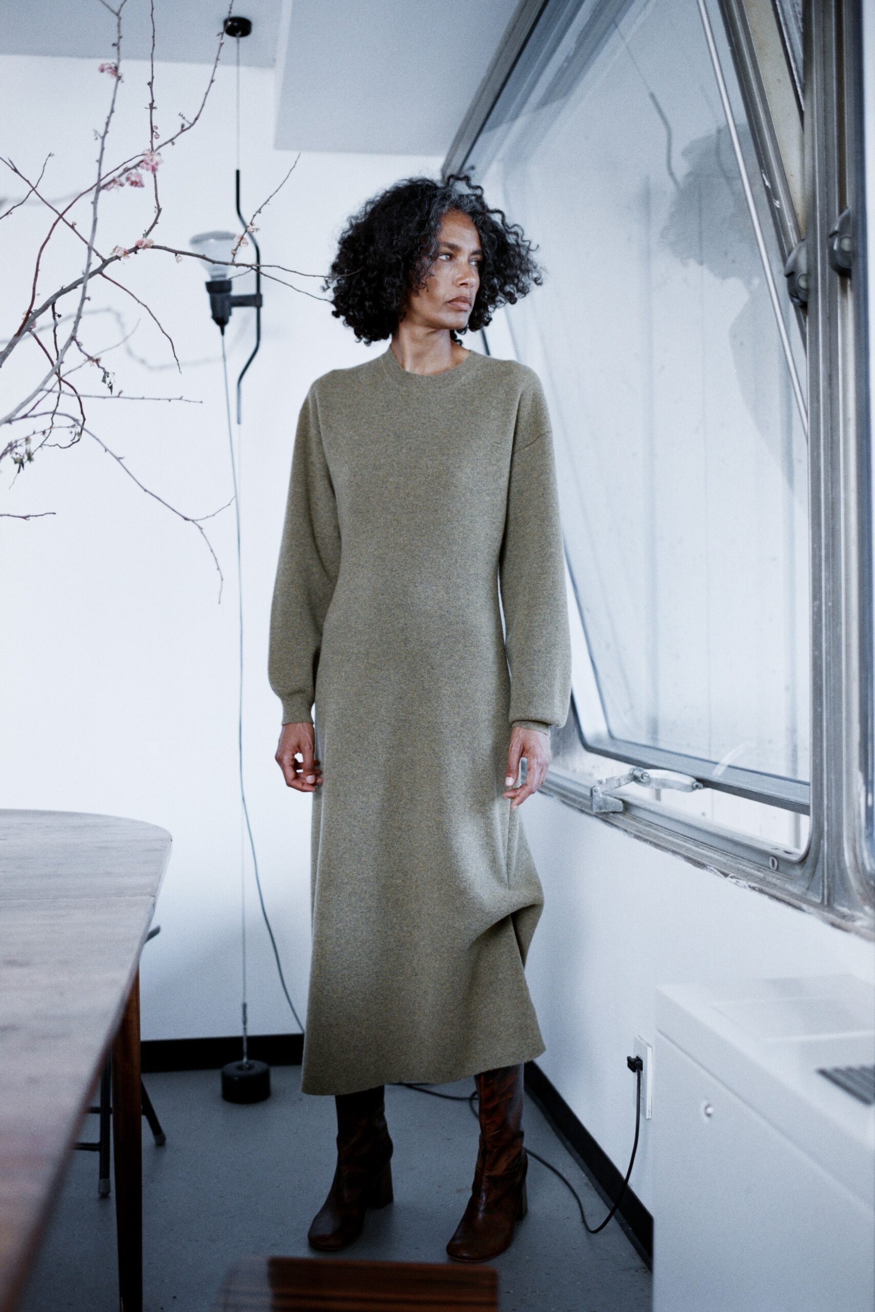 A fitted olive wool long-sleeve dress with an asymmetric design detail.