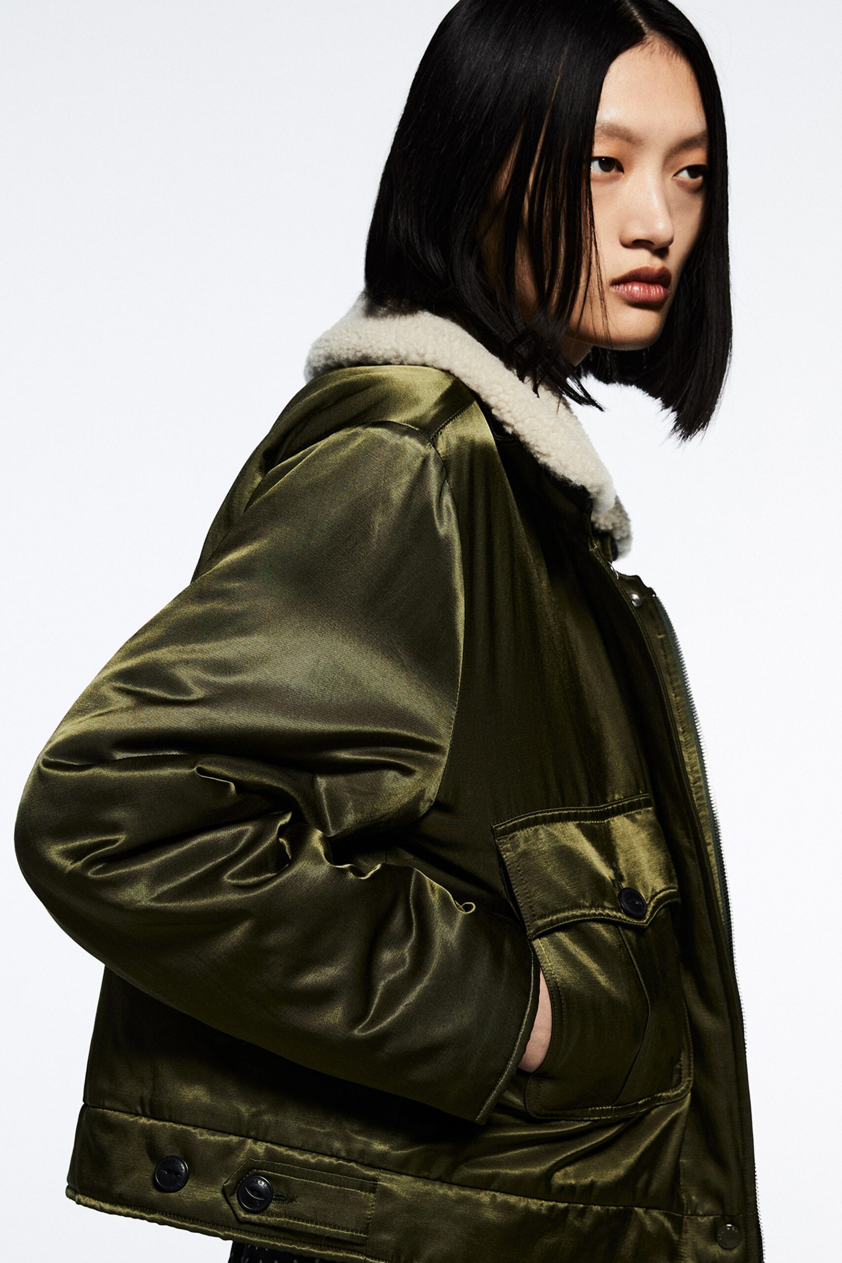 A relaxed green silk jacket with long sleeves and a collared design featuring a zippered detail.