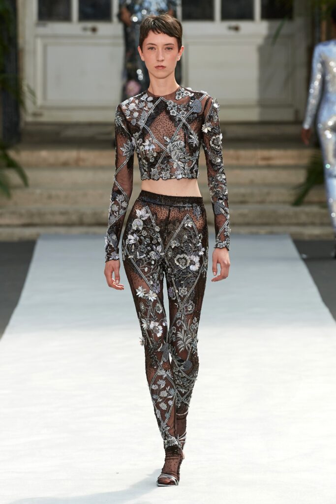 A fitted black mesh top with long sleeves and embroidered details paired with matching pants.