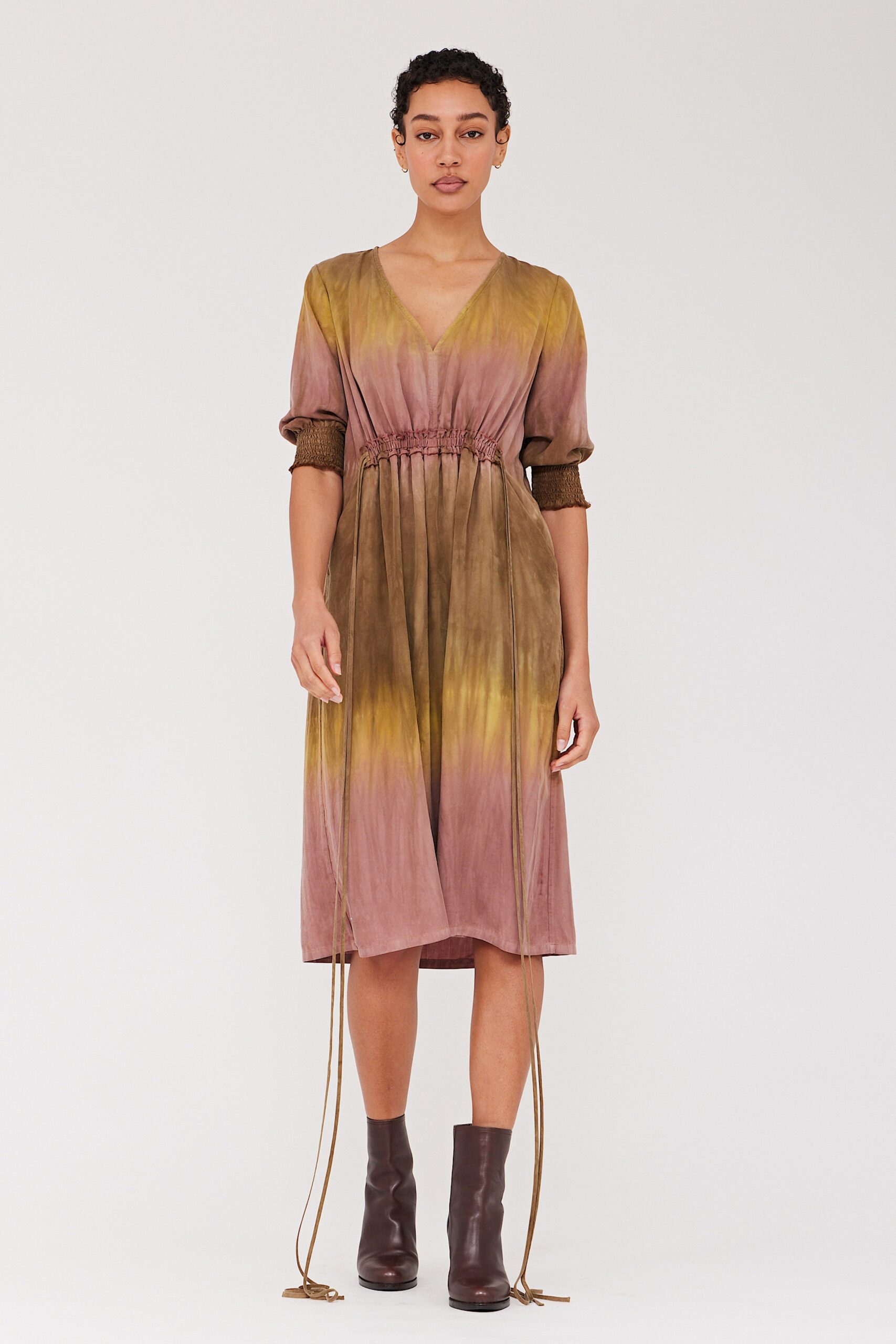 A relaxed brown, beige, and yellow tiered dress with a V-neckline and long sleeves.