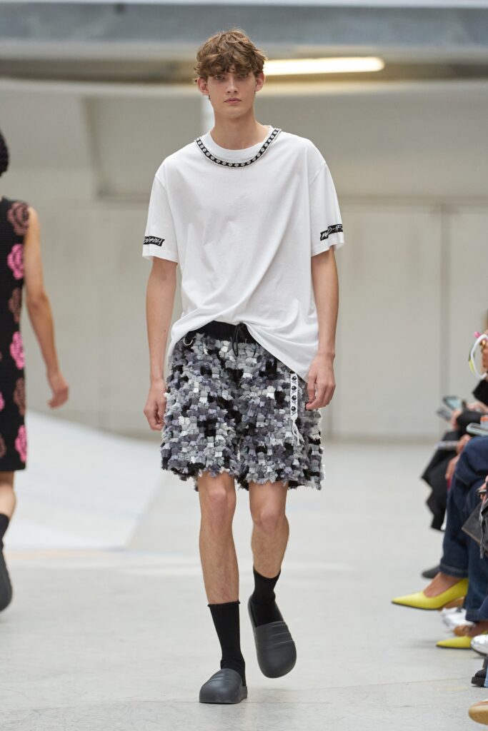 A relaxed white t-shirt with short sleeves paired with gray printed shorts.