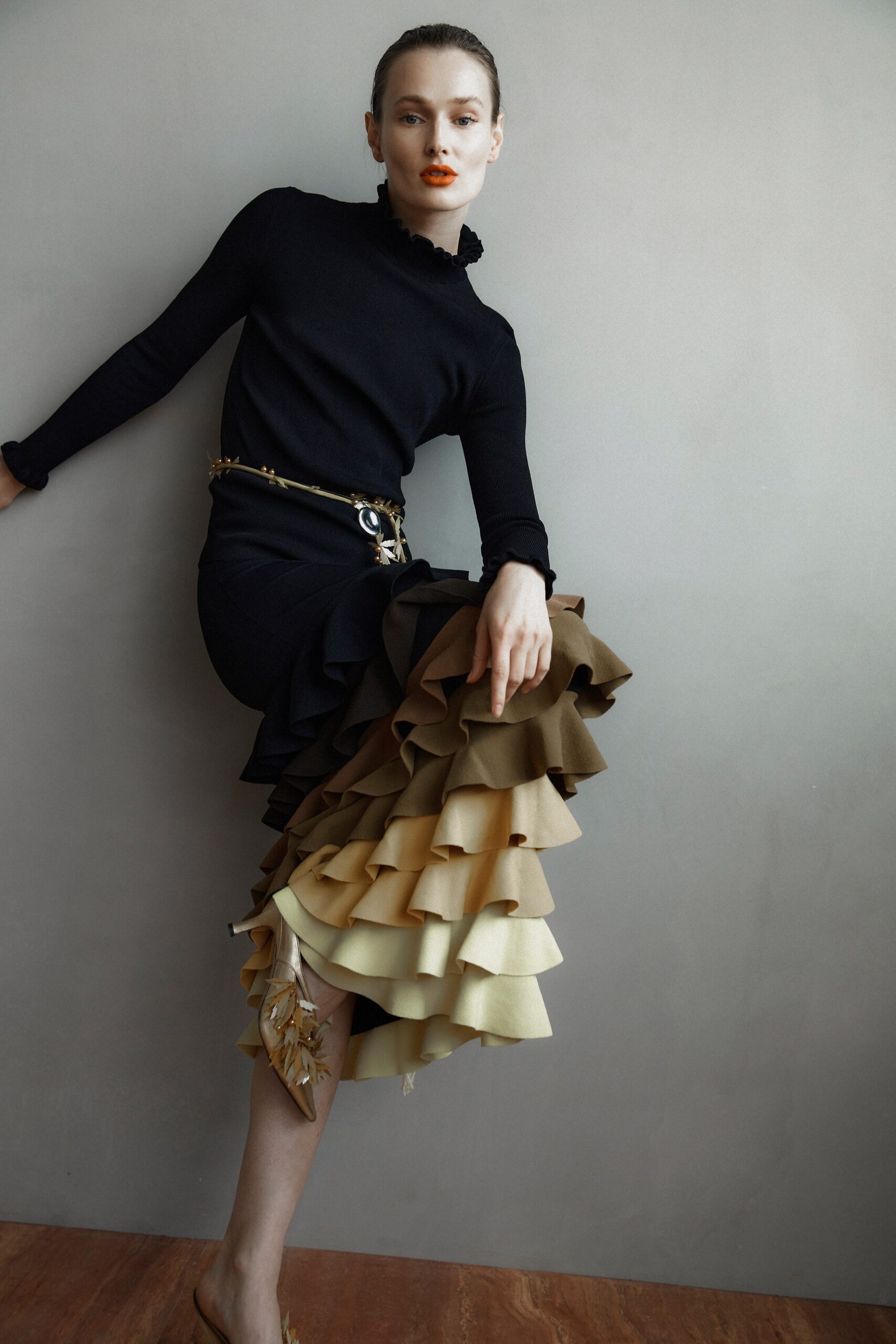 A fitted black dress with long sleeves, high neckline, and a tiered design in brown and cream.