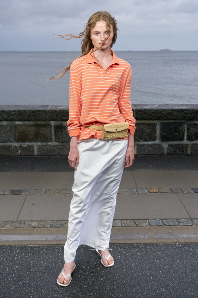 A relaxed orange striped long-sleeve shirt paired with a straight-leg white skirt.