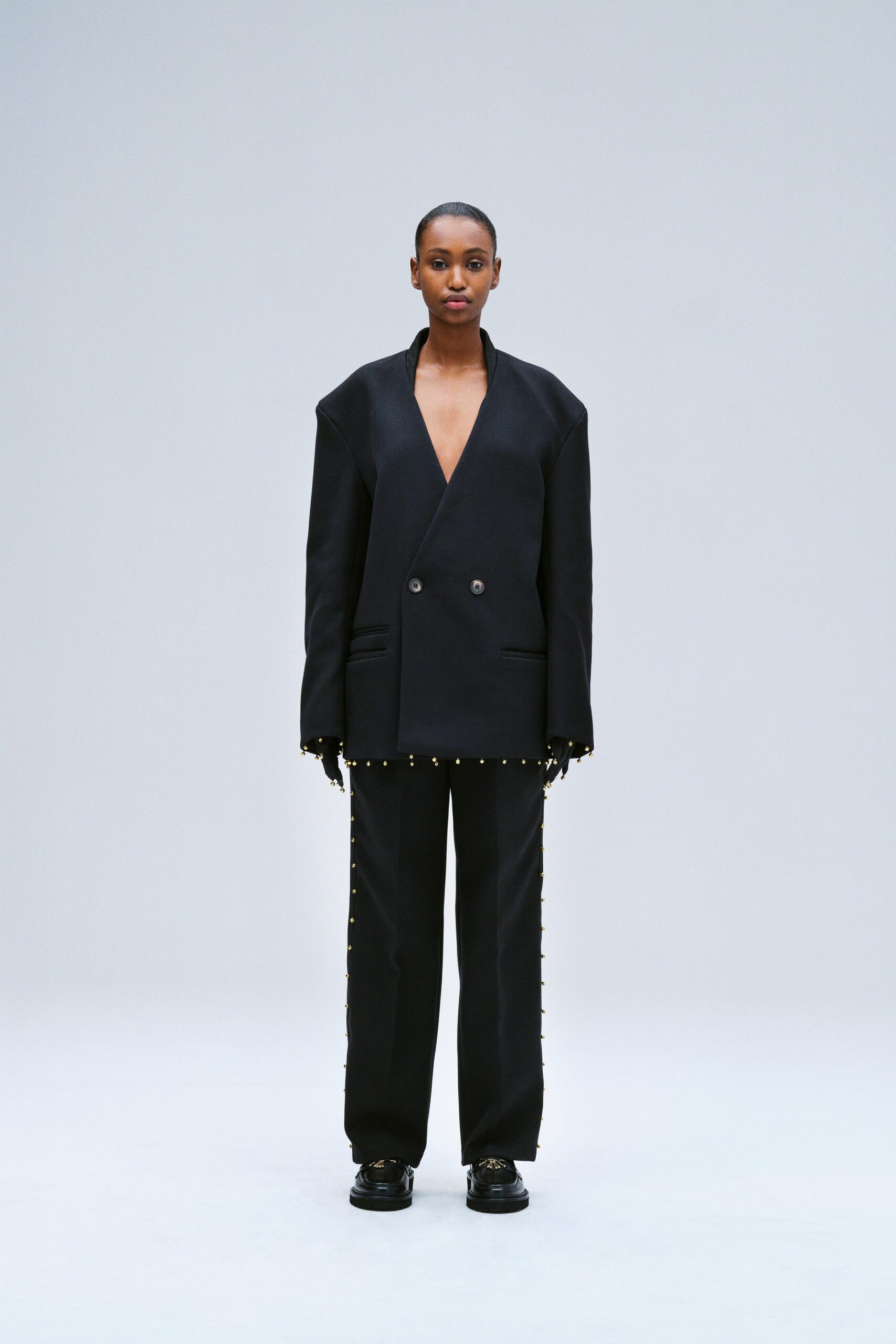 An oversized black blazer with a V-neckline paired with matching pants, featuring button details.