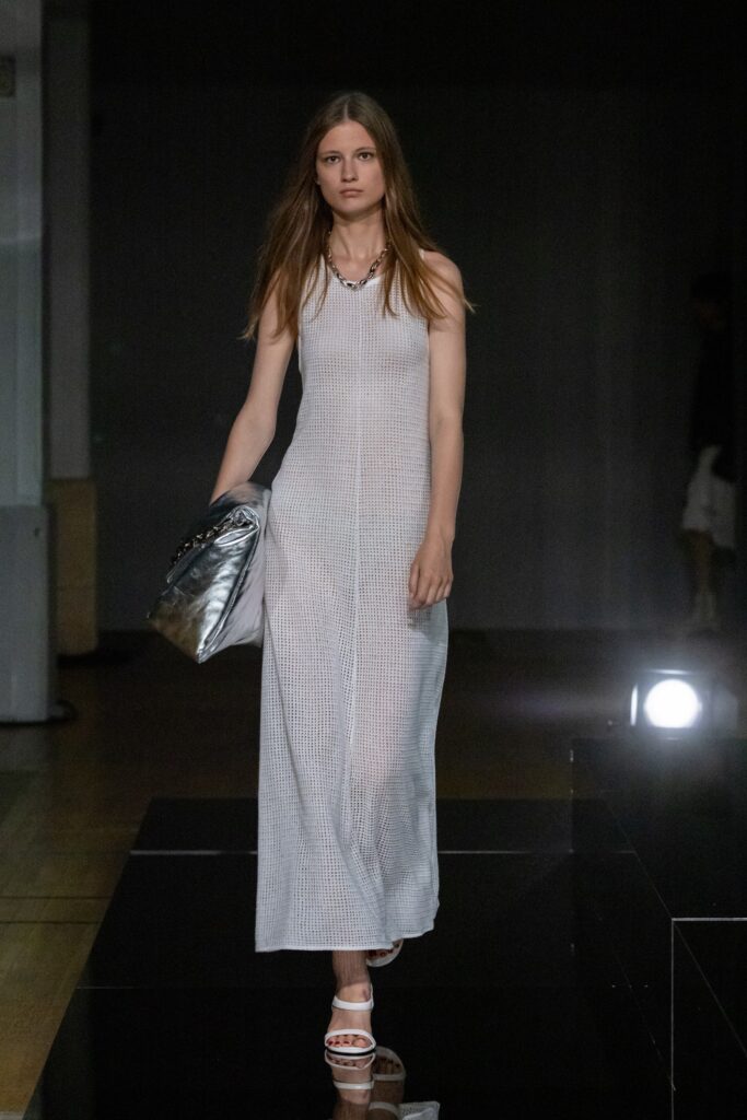 A fitted white cotton sleeveless dress with a high neckline and straight silhouette.