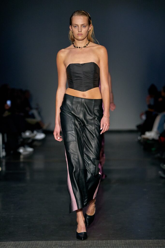 A fitted black leather sleeveless top paired with high-waisted straight-leg pants.