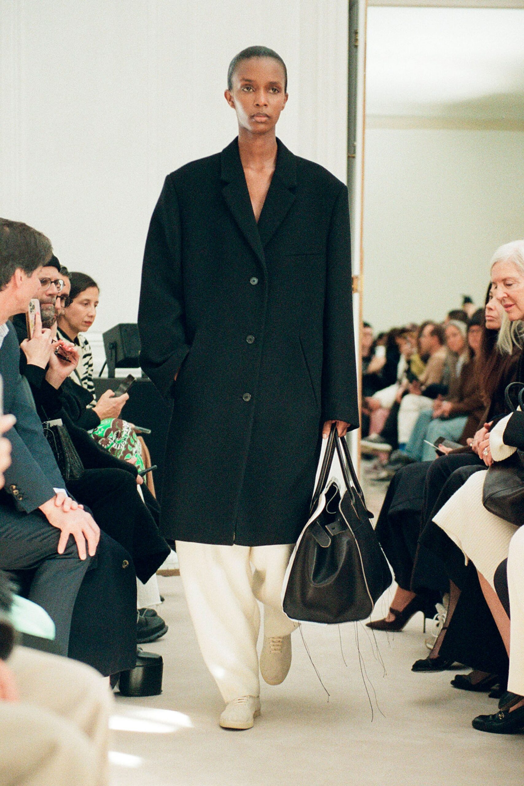 An oversized black wool coat with long sleeves and a collared design, featuring button details.