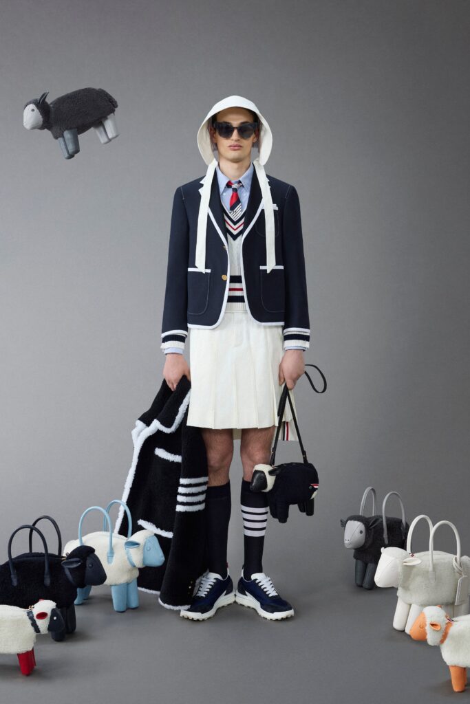 A fitted navy blazer with a collared neckline paired with a high-waisted pleated skirt.