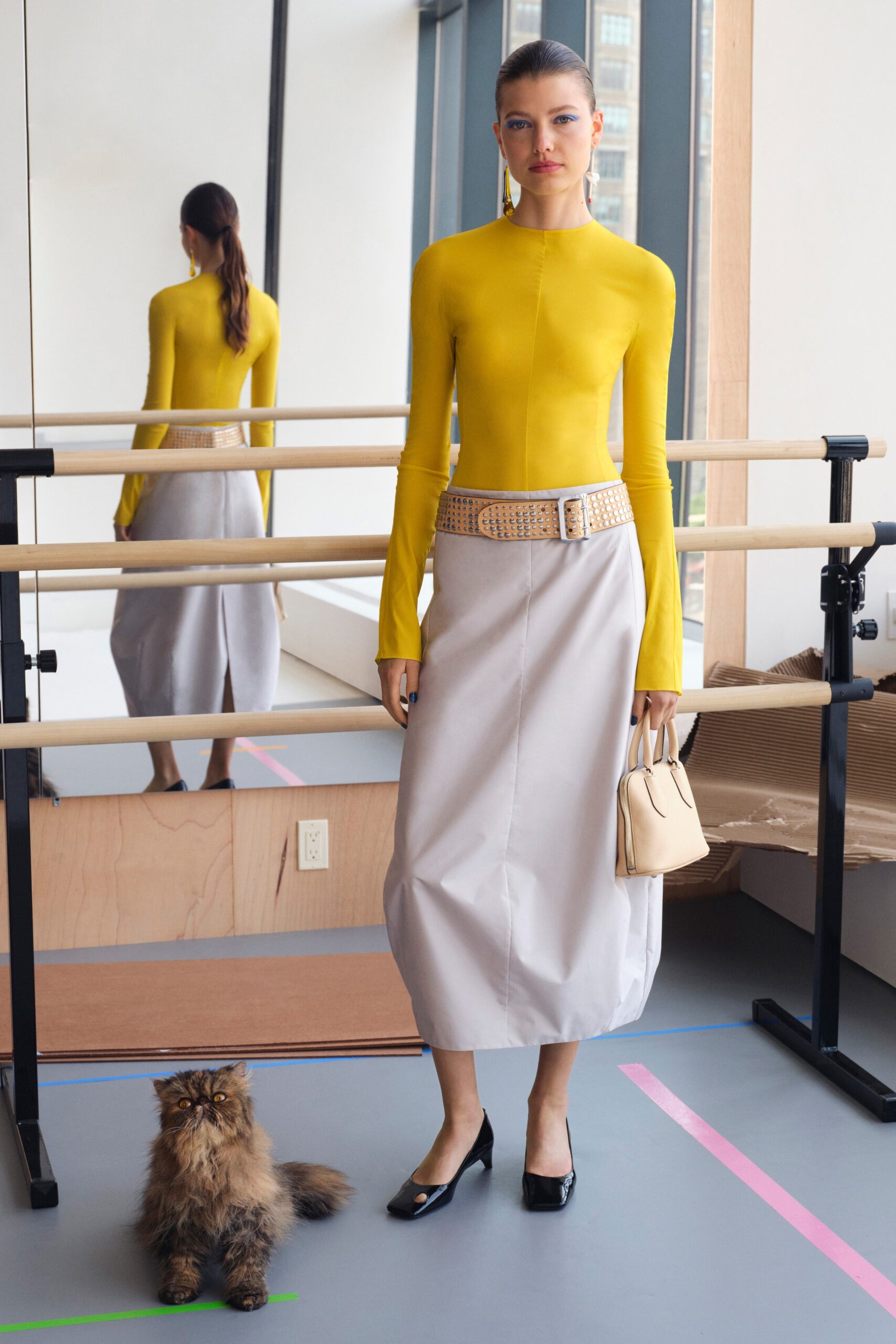 A fitted yellow long-sleeve top with a high-neck paired with an asymmetric gray skirt.