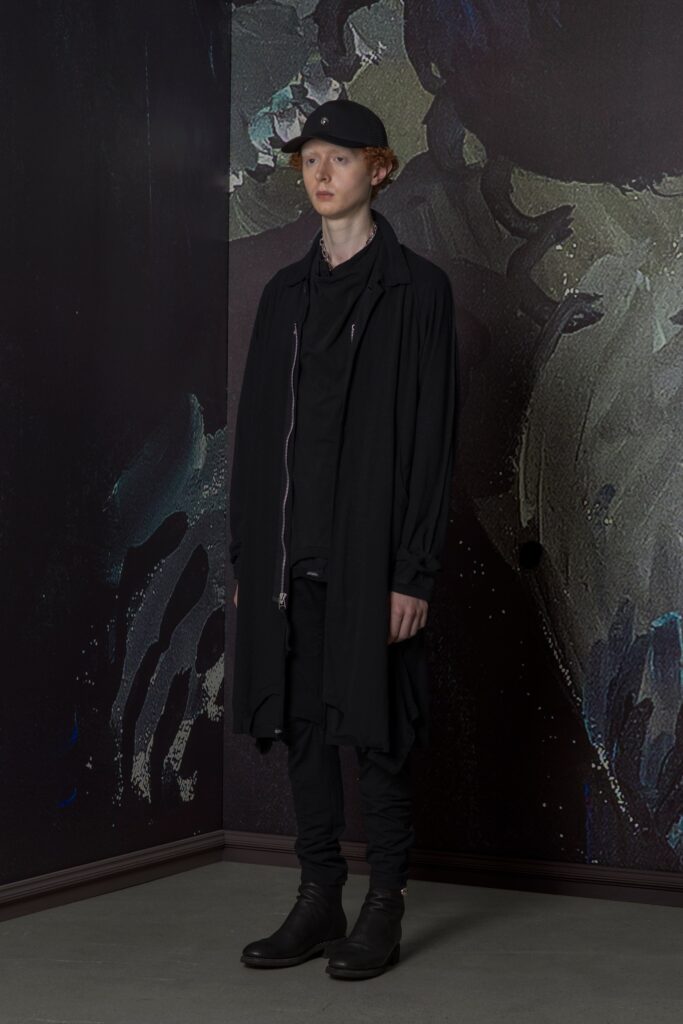 A relaxed black coat with long sleeves and asymmetric design paired with black pants.