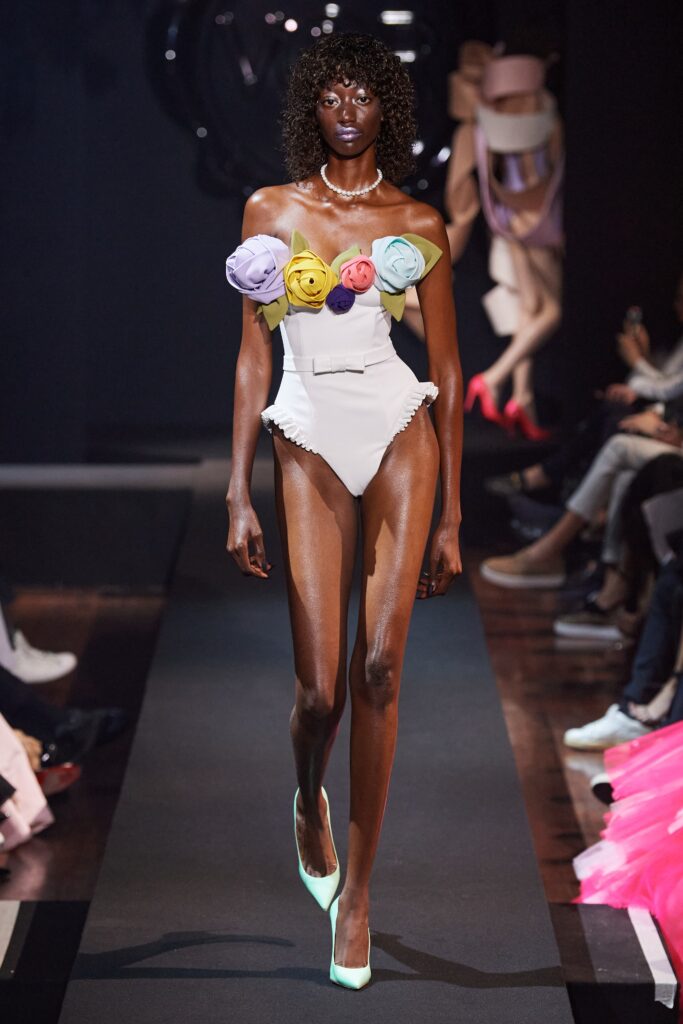 A fitted white strapless dress adorned with floral details, perfect for a runway look.