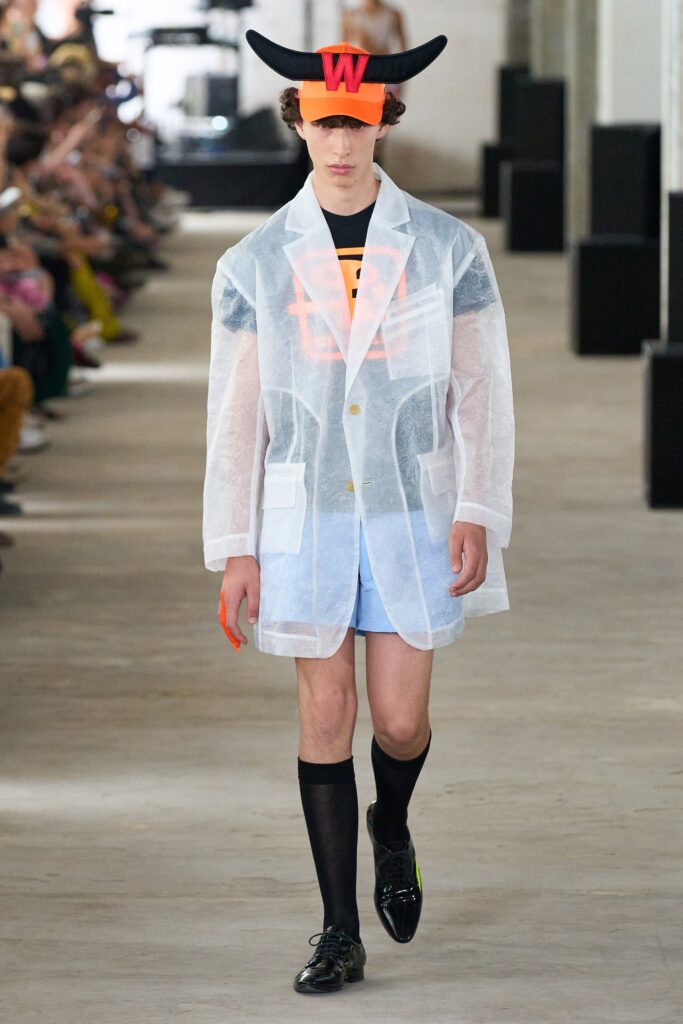 A relaxed white cotton jacket with long sleeves and a collared design paired with blue shorts.