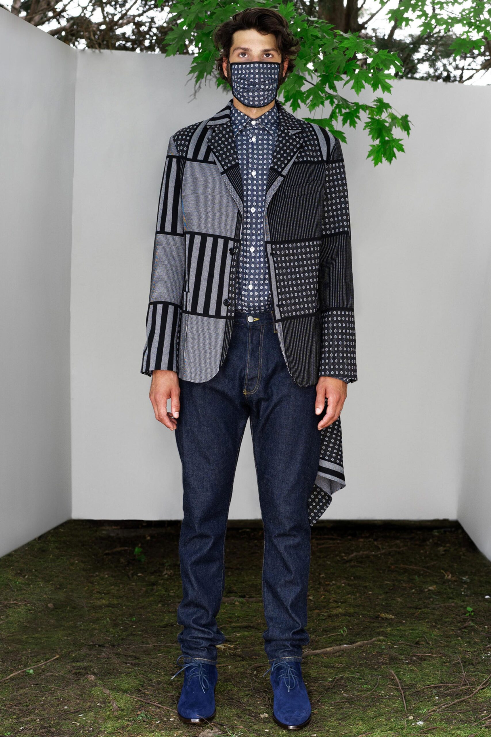 A relaxed black and blue jacket with a collared neckline and checked design, paired with denim pants.