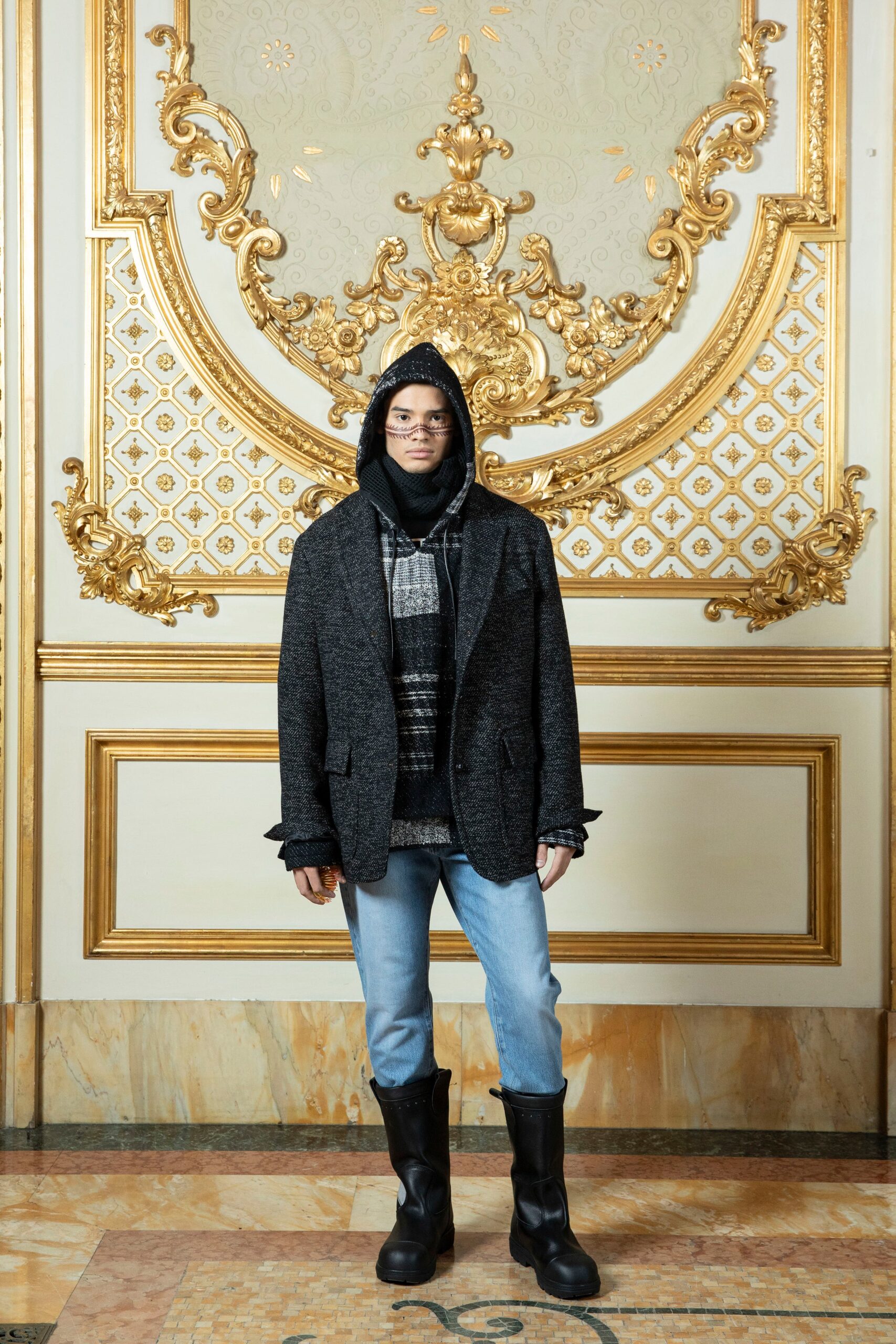 A relaxed black wool jacket paired with blue denim pants, featuring a hood for added style.