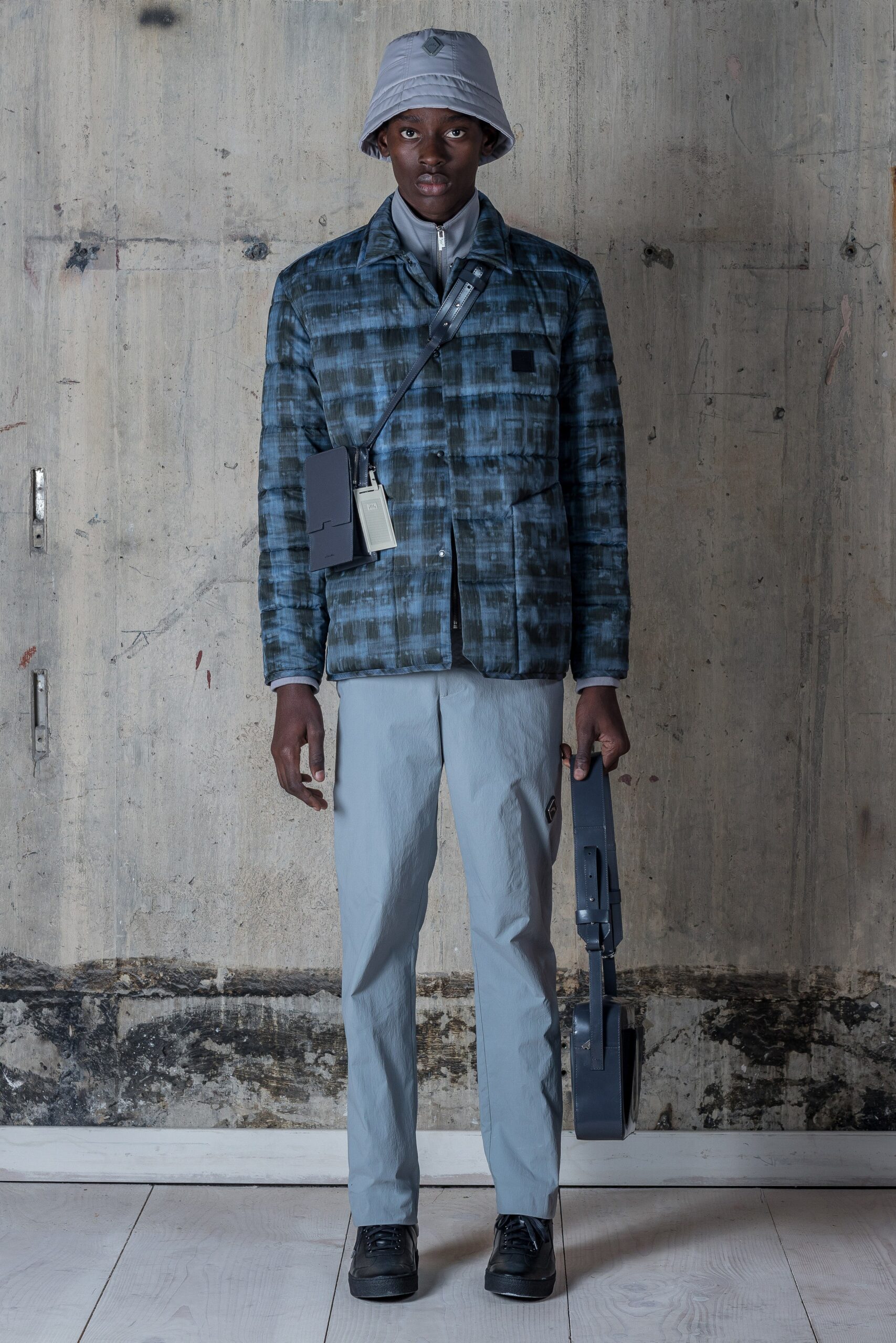 This relaxed-fit jacket features a striking blue checked pattern, complemented by a classic collared design. Paired with gray pants, the ensemble balances contemporary style with a laid-back aesthetic, making it versatile for various occasions.