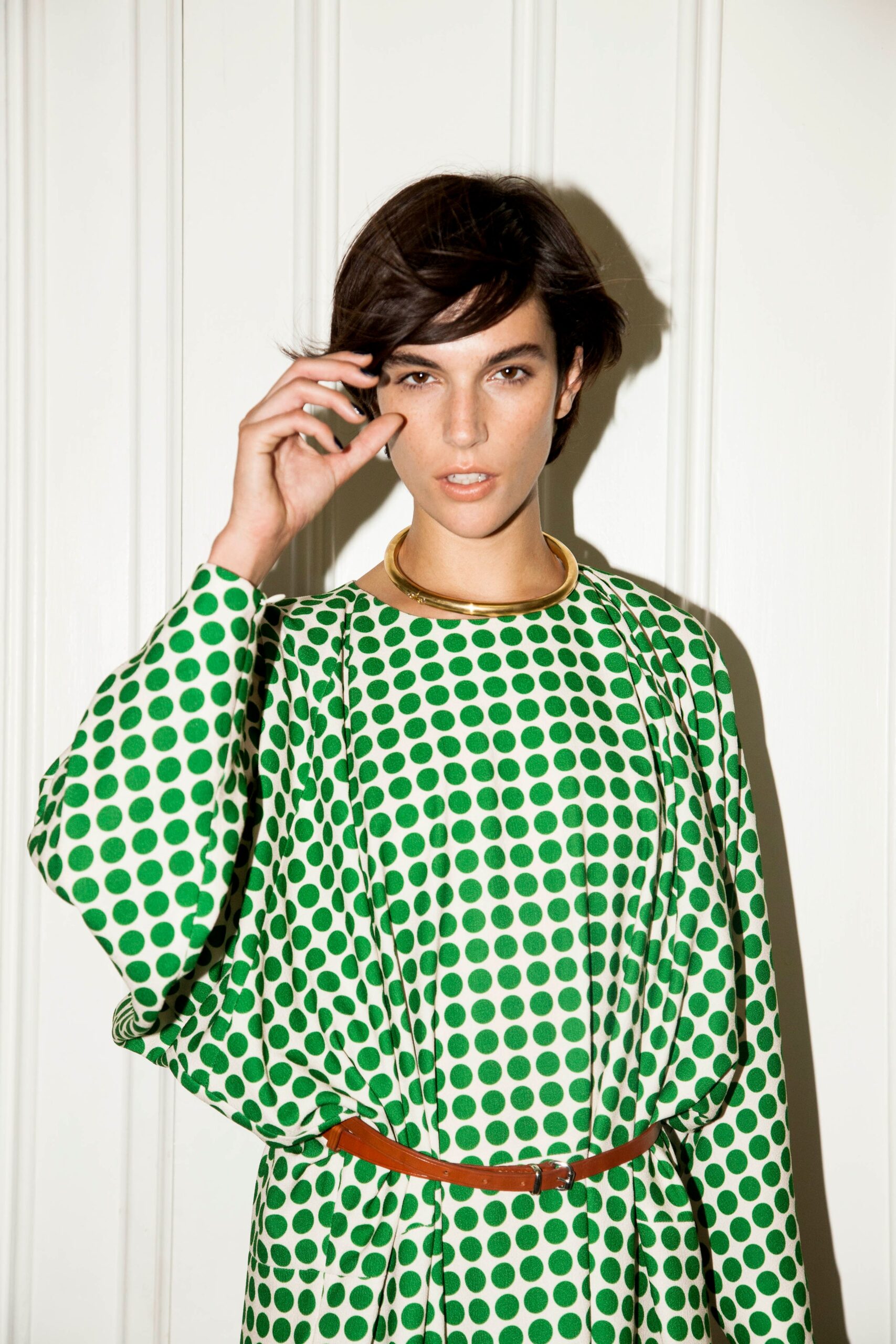 A relaxed green dress with long sleeves and a collared neckline featuring a polka-dot pattern.