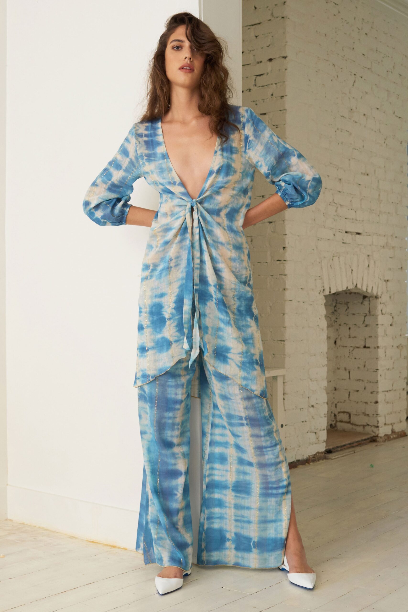 A relaxed blue silk top with a V-neckline paired with wide-leg pants featuring a printed design.