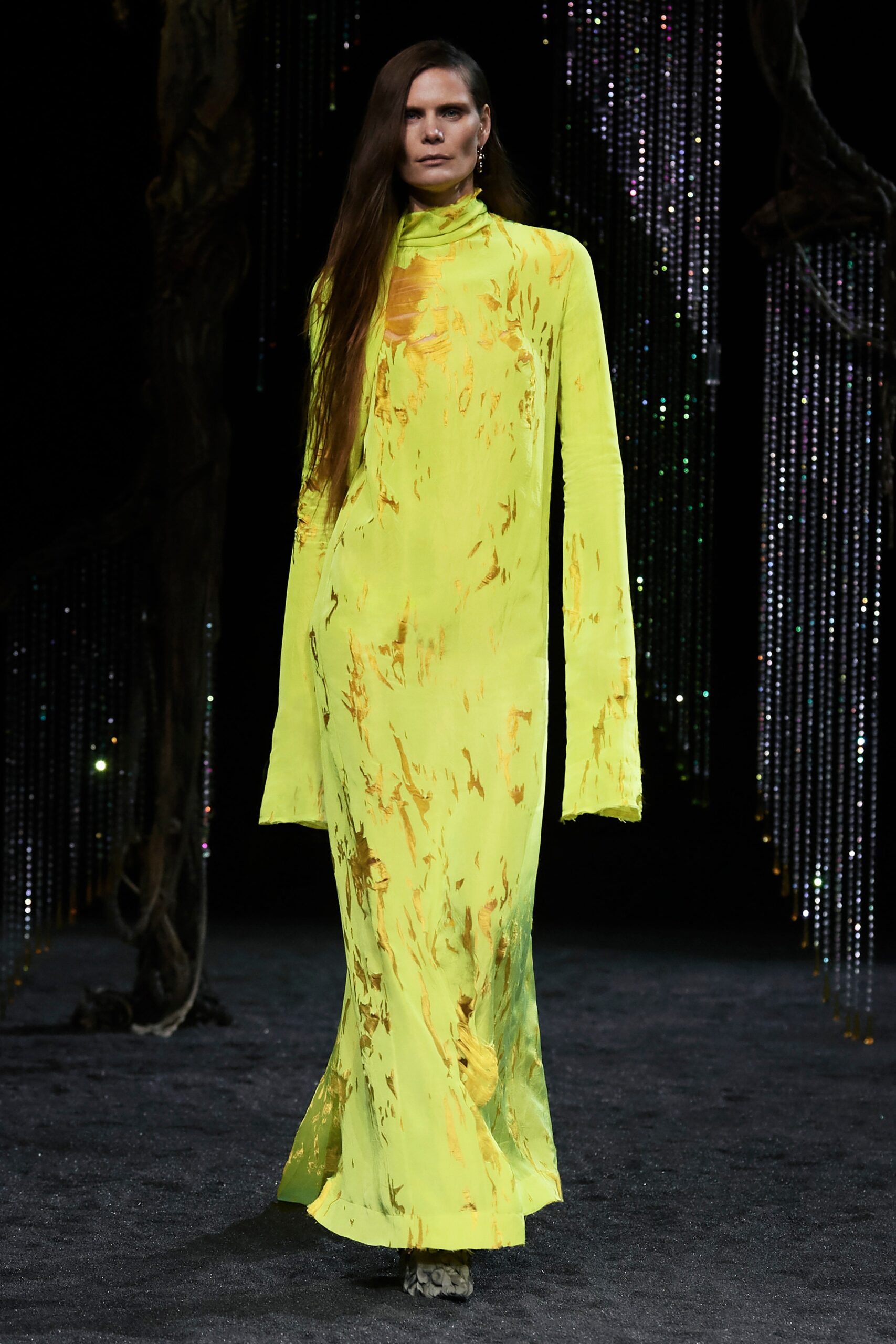 A fitted yellow silk dress with long sleeves and an asymmetric design.