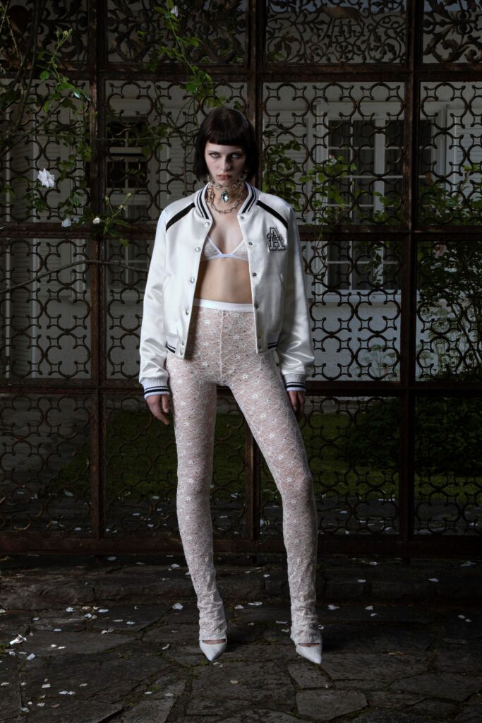 A fitted white long-sleeve jacket paired with sheer embroidered pants.