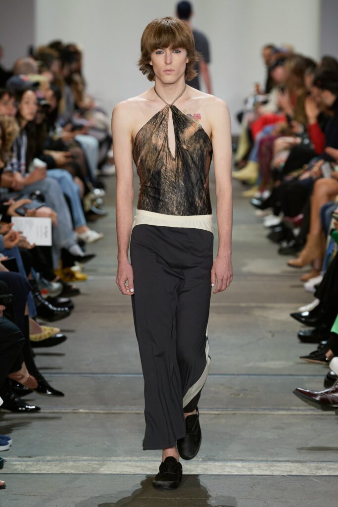 A fitted black silk halter top paired with gray pants featuring an asymmetric design.