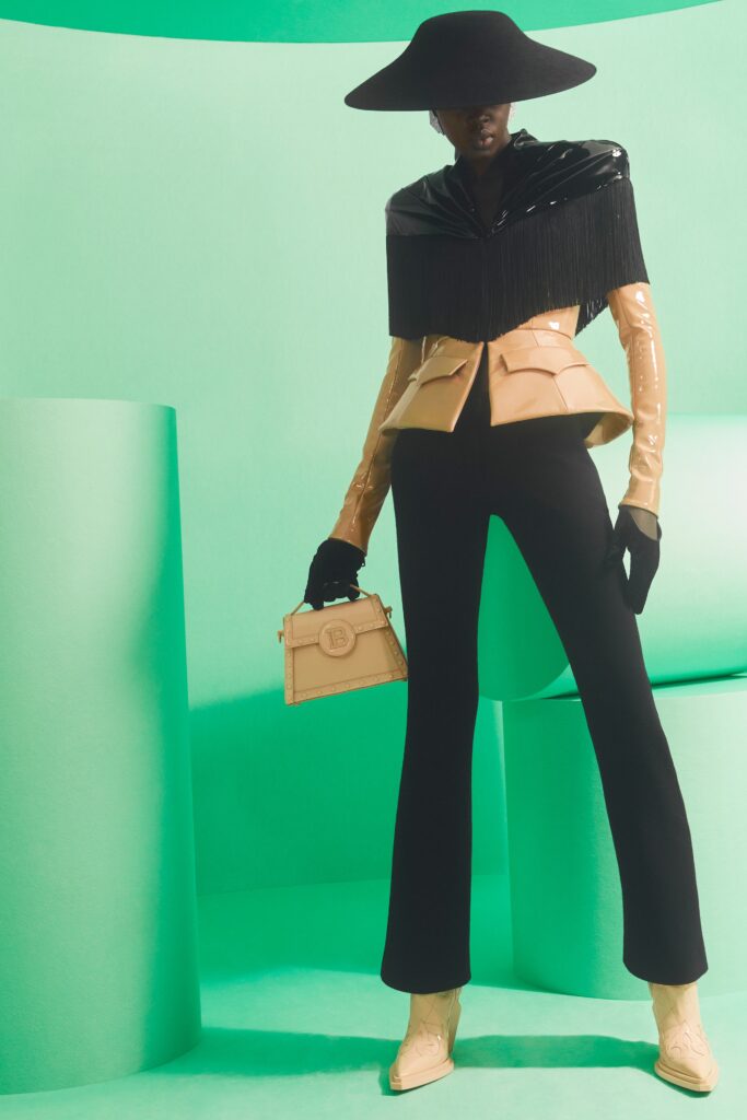 A fitted black leather jacket with fringes paired with tailored beige pants.