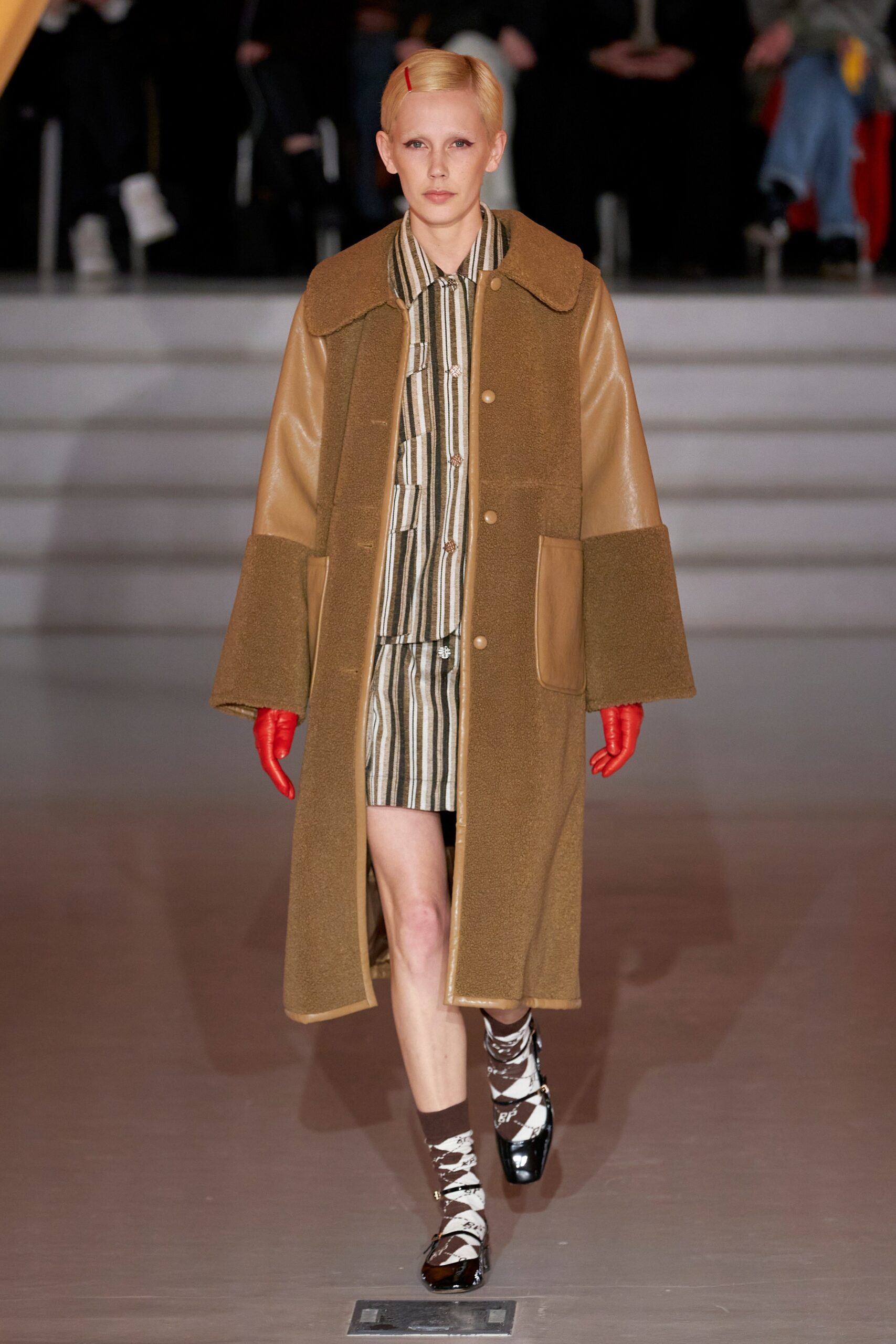 A relaxed brown leather coat worn over a striped dress with a collared neckline.