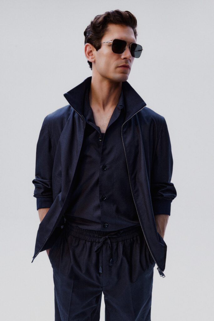 A relaxed black cotton jacket with a collared long-sleeve shirt underneath.