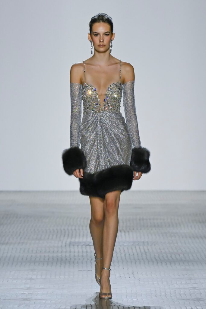 A fitted silver sequined dress with a deep V-neckline and draped silhouette.